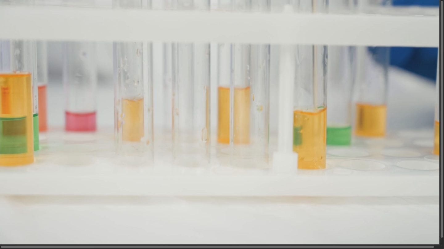 Racked test tubes of amber and green assay liquids in the laboratory