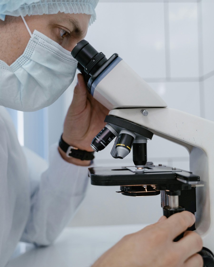 A scientist examining a slide under a laboratory microscope