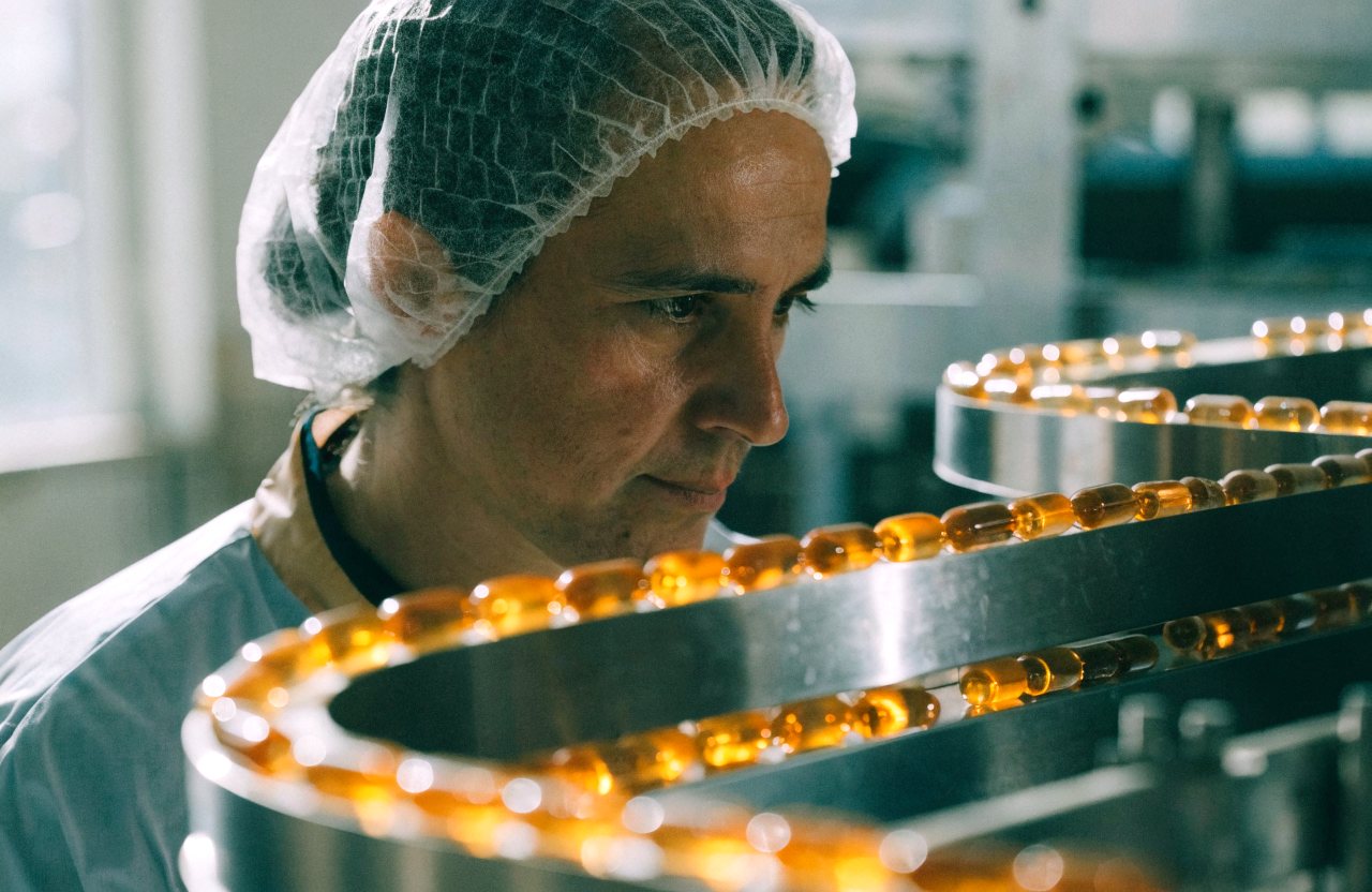 A production worker watching capsules move along a filling line